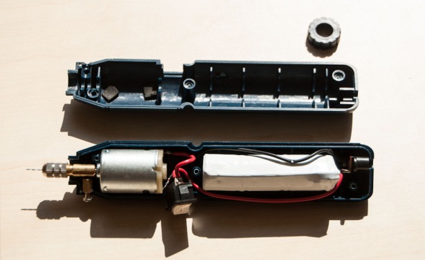 Elektrinis gręžtuvas su baterijomis iš graviravimo komplekto atidarytu korpusu